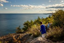 Boy and girl hiking across rocks by a lake, Lake Superior Provincial Park, Estados Unidos - foto de stock