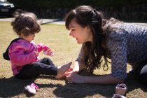 Ragazza seduta nel parco a giocare con un calzino con sua madre, Brasile — Foto stock