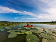Chico kayak en el lago lleno de nenúfares - foto de stock
