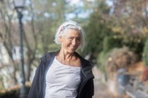 Портрет старшої усміхненої жінки, що стоїть в парку — стокове фото