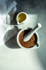 Fresh flax seeds in a mortar and pestle with a jug of olive oil — Stock Photo