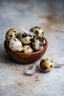 Wooden bowl filled with quail eggs and feathers — Stock Photo