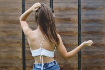 Rear view of a teenage girl standing outdoors touching her hair — Stock Photo
