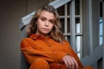 Portrait of a beautiful young woman sitting on a staircase in a hallway — Stock Photo