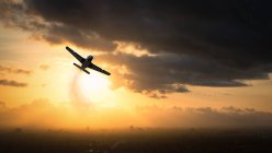 Silueta de un avión de la Segunda Guerra Mundial que vuela al atardecer, EE.UU. - foto de stock