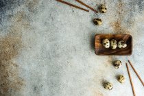 Overhead view of quail eggs in an Asian dish with chopsticks — Stock Photo