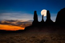 Lune se levant derrière une silhouette de Trois Sœurs, Monument Valley, Arizona, USA — Photo de stock