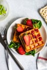 Overhead view of a plate of waffles with strawberries and mint, and a glass of mint water — Stock Photo