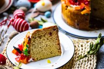 Slice of Easter cake with glace fruit on a table with Easter decorations — Stock Photo
