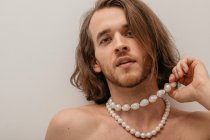 Portrait of a handsome shirtless man wearing pearl necklaces — Stock Photo