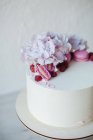 Торт з різнокольоровими солодкими макарунами та квітами на столі, вид зверху — стокове фото