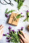 Kinderhände sind bereit für das Einwickeln von Geschenkschachteln zum Muttertag und dekorieren mit frischen Lavendelblüten auf Betongrund — Stockfoto