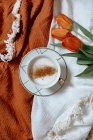 Xícara de café e um cappuccino com um buquê de tulipas brancas em um fundo de madeira marrom — Fotografia de Stock