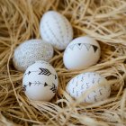 Primer plano de cinco huevos de Pascua decorados en un nido de pájaros - foto de stock