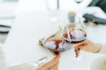 Due donne fanno un brindisi celebrativo con bicchieri di vino rosso — Foto stock