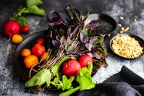 Concept d'alimentation saine avec des légumes crus et des herbes sur plaque de céramique noire avec des graines sur fond de pierre sombre — Photo de stock