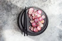 Fette di verdure di ravanello fresche biologiche su piatto di pietra con bacchette — Foto stock