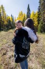 Портрет женщины, стоящей в лесу, держащей свою маленькую дочь, Калифорния, США — стоковое фото