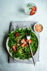 Bowl with organic salad with rucola and strawberry on concrete table — Stock Photo