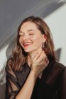 Portrait of a beautiful woman with her hand on her neck laughing — Stock Photo