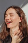 Portrait of a beautiful with her hand on her neck laughing — Stock Photo