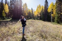 Retrato de una mujer de pie en el bosque sosteniendo a su hija pequeña, California, EE.UU. - foto de stock