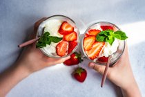 Postre de helado de verano servido con fresas y menta en las manos del niño - foto de stock