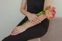 Primo piano di una donna in abito da sera seduta su un divano con un fiore di Amarillide — Foto stock