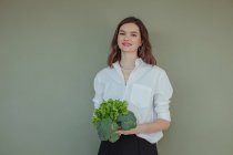 Retrato de una hermosa mujer sonriente sosteniendo brócoli fresco y lechuga - foto de stock
