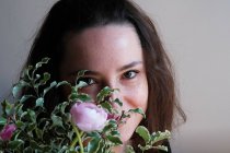 Портрет усміхненої жінки, що тримає купу квітів перед обличчям — стокове фото