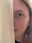 Close-Up of a girl hiding behind a curtain — Stock Photo