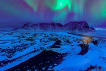 Northern lights over Vestrahorn mountains landscape and distant person, Stokksnes Peninsula, Islândia — Fotografia de Stock