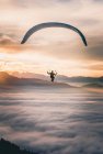 Hombre Parapente sobre las nubes al atardecer, Salzburgo, Austria - foto de stock