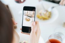 Mujer tomando una foto de su comida en un restaurante - foto de stock