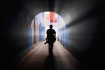 Silueta de hombre con una cámara caminando a través de un túnel en Chefchaouen, Marruecos - foto de stock