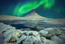 Northern lights over frozen lake and Kirkjufell rock, Islândia — Fotografia de Stock