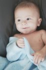 Close-up of a smiling baby boy holding a blanket — Stock Photo