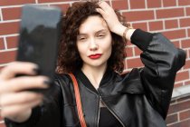 Beautiful woman standing in street taking a photo of herself — Stock Photo