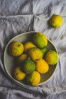 Ciotola di gres pieno di limoni organici su sfondo tessile — Foto stock