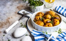 Köstliche neue Kartoffeln in einer Schüssel mit gehacktem Thymiankraut, serviert auf einem Betontisch — Stockfoto