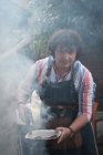 Portrait of a man cooking sausages on a  barbecue — Stock Photo