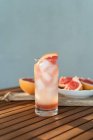 Склянка води зі свіжими грейпфрутовими і грейпфрутовими сегментами на столі — стокове фото