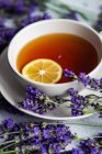 Xícara de chá com limão e flores frescas de lavanda no fundo de concreto — Fotografia de Stock