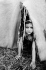 Serious girl looking out from a inside a torn tent — Stock Photo