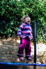 Chica feliz saltando en un trampolín en el jardín, Italia - foto de stock