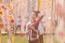 Portrait of a smiling woman in traditional Thai clothing holding a parasol, Thailand — Stock Photo