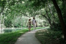 Casal feliz caminhando um longo caminho por um rio no verão, França — Fotografia de Stock