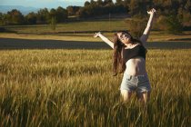 Teenage girl standing in meadow with her arms outstretched, Spain — Stock Photo