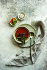 Літній томатний суп, який подають у мисці зі спеціями та травами на бетонному фоні — стокове фото