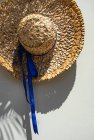Вид зверху на літню солом'яну шапку з синьою стрічкою на столі — стокове фото